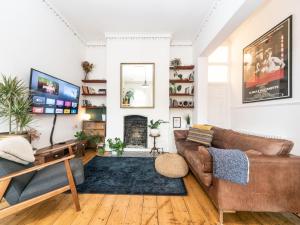 uma sala de estar com um sofá castanho e uma lareira em Pass the Keys Rustic and Quirky Flat in Charming Charlton Village em Londres