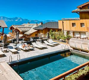 uma piscina num resort com pessoas deitadas em espreguiçadeiras em Grandes Rousses Hotel & Spa em Alpe-d'Huez