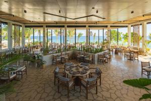 a restaurant with tables and chairs and the ocean in the background at Aldiana Club Zanzibar Kwanza in Kizimkazi