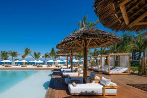 a resort pool with lounge chairs and umbrellas at Aldiana Club Zanzibar Kwanza in Kizimkazi
