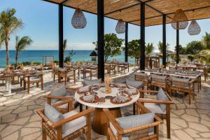 een restaurant op het strand met tafels en stoelen bij Kwanza Resort by SUNRISE in Kizimkazi