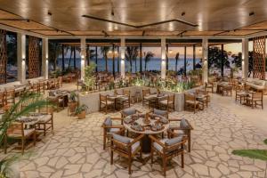 a restaurant with tables and chairs and the ocean at Aldiana Club Zanzibar Kwanza in Kizimkazi