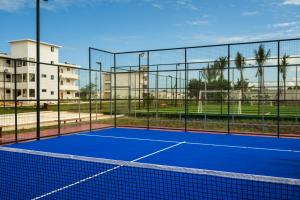 a tennis court with a net and buildings in the background at Aldiana Club Zanzibar Kwanza in Kizimkazi
