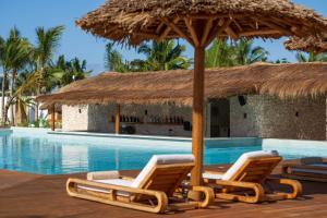 a swimming pool with two lounge chairs and an umbrella at Aldiana Club Zanzibar Kwanza in Kizimkazi