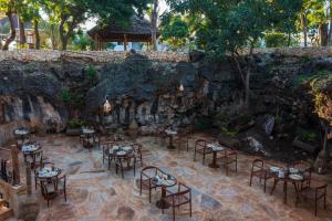 a restaurant with tables and chairs in front of a stone wall at Aldiana Club Zanzibar Kwanza in Kizimkazi