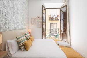 Un dormitorio con una cama blanca y una ventana. en Apartamentos Luna Suites Palacio Dorita, en Granada