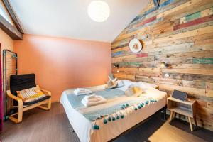 a bedroom with a wooden wall with a bed and a chair at Chez Malou & Hugo vue lac proche Suisse & stations ! in Saint-Gingolph