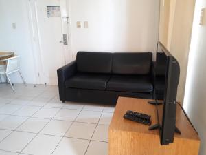 a living room with a black couch and a television at Silva Hospedagem AMERICAN FLAT BEIRA MAR apartamento por temporada in São Luís