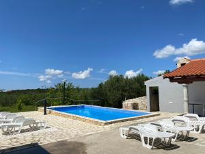 a swimming pool with white chairs next to a house at Guest Accommodation Grozdanić in Dubravice