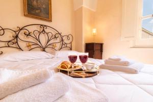 a bed with a tray of food and two glasses of wine at Palazzo Zacà in Gallipoli