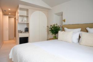 a bedroom with a white bed with a vase of flowers at Lou Cagnard in Saint-Tropez +37 photos