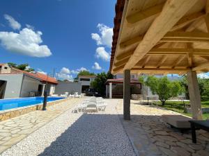 a large wooden pavilion with chairs and a swimming pool at Guest Accommodation Grozdanić in Dubravice