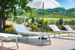3 sillas y una mesa con sombrilla en TidHouse - Bed and Breakfast with private pool and free parking, en Motta