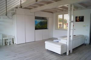 a white room with a couch and a tv on the wall at Charme Lake Loft in Ispra