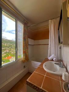 a bathroom with a sink and a tub and a window at Hôtel Miramar in Vence