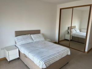 een slaapkamer met een groot bed en een spiegel bij Modern 2 bed flat with balcony in Southend-on-Sea