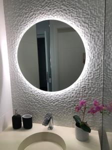 a bathroom with a sink with a mirror and flowers at Villa El Buzo in Zahara de los Atunes