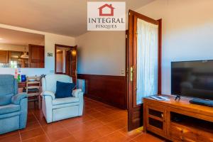 a living room with two chairs and a flat screen tv at La Masia de la Fosca in Palamós