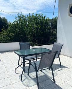 a glass table and two chairs on a patio at Villa Loukas in Loutsa