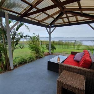un patio cubierto con sofá y mesa en Stunning lakefront 4-bedroom, 2.5-bath home en Gorokan