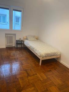 una cama en una habitación con suelo de madera en Amplio apartamento en La Arena, 4 hab, en Gijón 16 fotos más