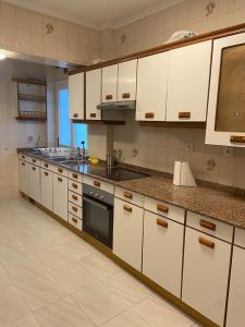 cocina grande con armarios blancos y fregadero en Amplio apartamento en La Arena, 4 hab, en Gijón