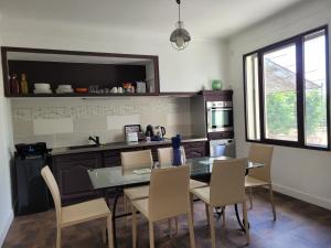 a kitchen with a glass table and chairs in it at MAS TAREAU LE DAMIER in Beaucaire