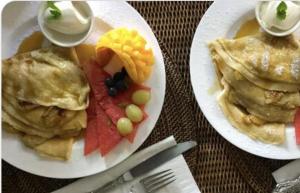 two plates of food with eggs and fruit on a table at Olive Tree Cottage in Central Tilba