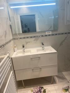 bagno con lavandino bianco e specchio di Agréable chambre a Menucourt