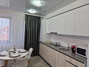 a kitchen with a table and a sink and a microwave at Crystal Sands Residence in Eforie Nord