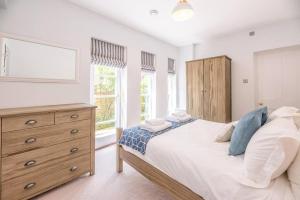 a bedroom with a bed and a dresser and windows at Sea House in Southwold