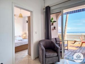 - une chambre avec une chaise, un lit et un balcon dans l'établissement Les Mosalas - 2 et 3 étoiles - pieds dans l'eau - Lagon de Saint-Leu, à Saint-Leu