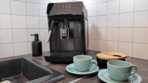 a coffee maker sitting on a kitchen counter with two cups at GoldenApart Apartamenty 2-sypialniowe - Grzany Basen - Kameralny Klimat in Krynica Morska