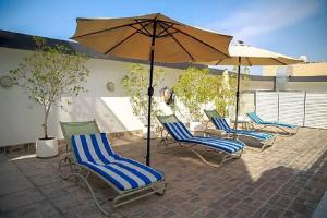 eine Gruppe Stühle und ein Sonnenschirm auf einer Terrasse in der Unterkunft Versailles by Raviz Hotel in Dubai