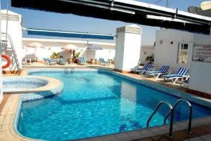 ein großer Pool mit blauen Stühlen und Sonnenschirmen in der Unterkunft Versailles by Raviz Hotel in Dubai