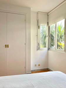 um quarto com uma cama branca e uma janela em Luminoso apartamento frente al mar con piscina em Roses
