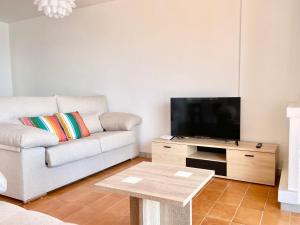 uma sala de estar com um sofá e uma televisão de ecrã plano em Luminoso apartamento frente al mar con piscina em Roses