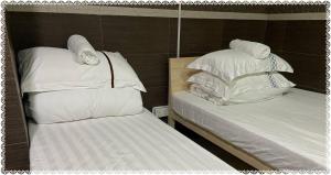 2 Betten mit weißer Bettwäsche und Kissen in einem Zimmer in der Unterkunft 安捷賓館 Famous Guest House in Hongkong