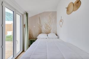 Bett in einem Zimmer mit einem großen Fenster in der Unterkunft Calme et detente aux Sables d Olonne in Les Sables-dʼOlonne