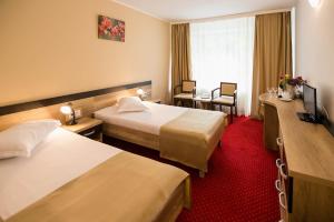 um quarto de hotel com duas camas e um tapete vermelho em Complex Balnear Cozia em Călimăneşti