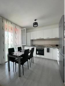 a white kitchen with a table and chairs in it at Apartament Melanie in Oradea
