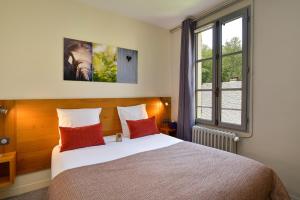 Un dormitorio con una cama con almohadas rojas y una ventana en Moulin des Templiers Hôtel & SPA, en Pontaubert