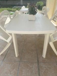 biały stół i krzesła z doniczką w obiekcie Agréable chambre w mieście Menucourt