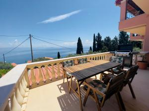 balcón con mesa de madera y 2 sillas en Green Horizon 3 BR House with Sea View en Benitses