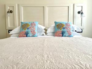 uma cama branca com almofadas azuis e uma cama grande com em Le Camere di Libero e Roberta em Tropea
