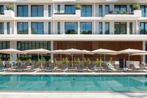 a hotel with a swimming pool with chairs and umbrellas at Martinhal Lisbon Oriente in Lisbon