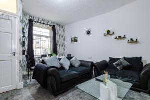 a living room with a black couch and a table at 65 inch TV in Modern 2 Bed Hideaway in Bradford