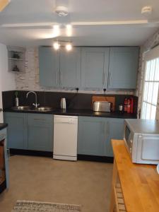 una cocina con armarios azules y electrodomésticos blancos en Lovely Wee House in Lundin Links perfect beaches, en Lundin Links