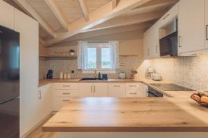 a kitchen with white cabinets and a wooden counter top at Melena Premium Suites in Roda