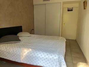 1 dormitorio con 1 cama con edredón blanco en Saint-Raphaël, Boulouris, F2 dans belle résidence 3 piscines, proche bord de mer, en Saint-Raphaël